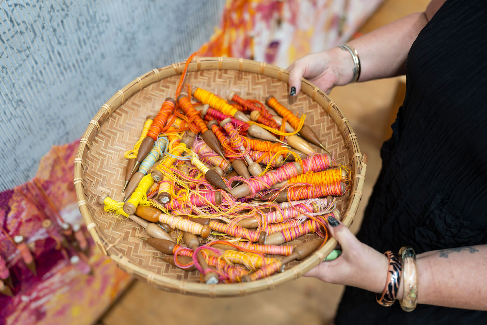 ATW Weavers Emma Sulzer and Saffron Gordon work on a vibrantly coloured tapestry with baskets of bobins surrounding them.