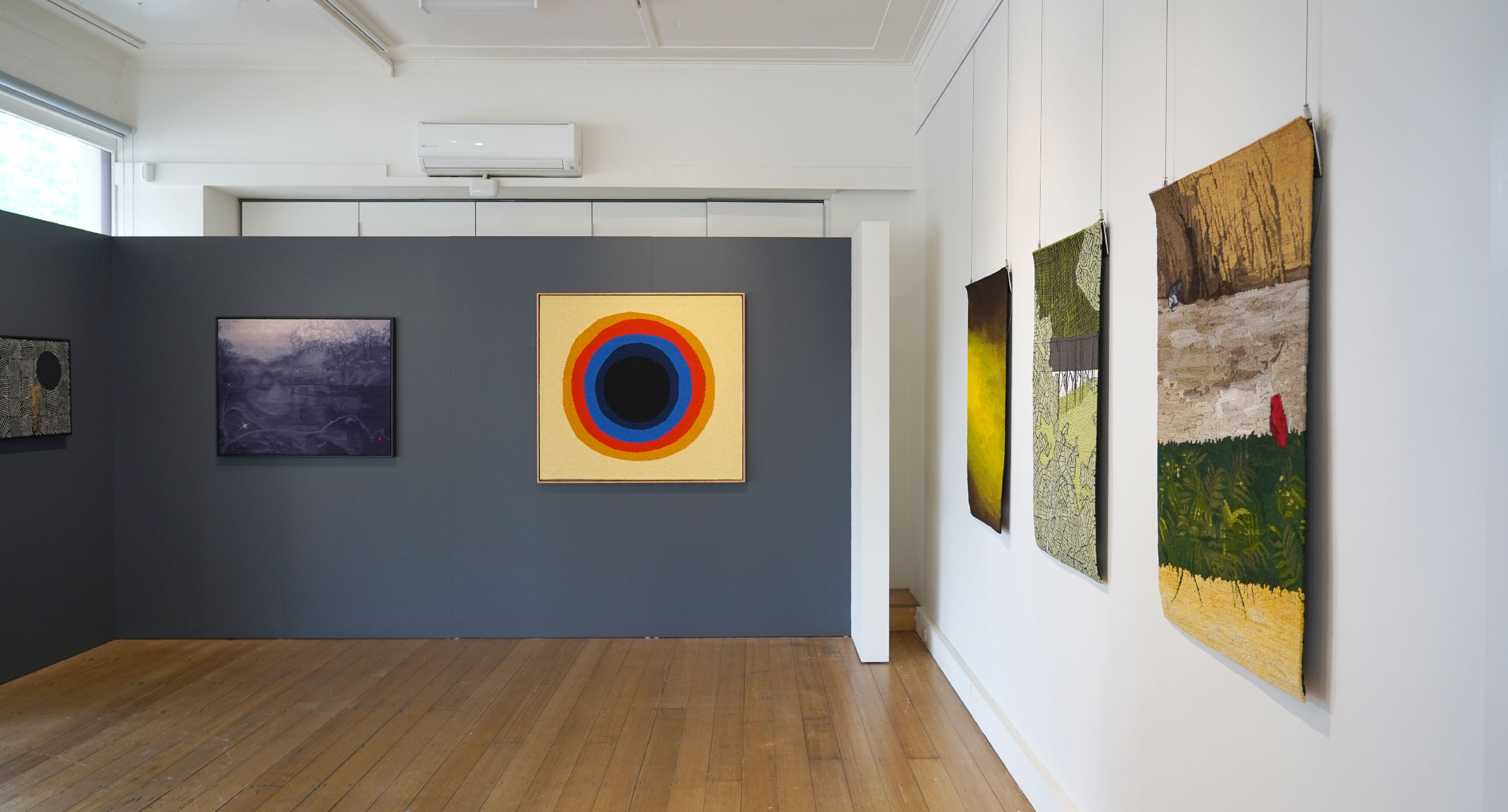 A gallery space with brightly coloured textile artworks on the walls